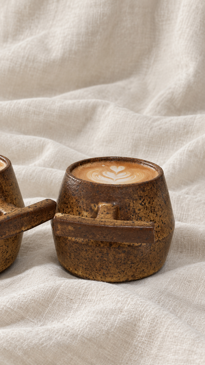 Death Valley handmade ceramic mugs with brown and ochre glaze, dark speckles and sculptural handles on offwhite linen
