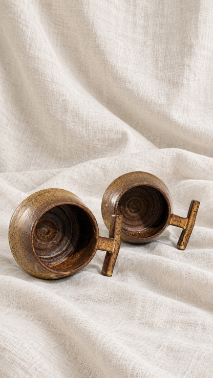 Death Valley handmade ceramic mugs with brown and ochre glaze, dark speckles and sculptural handles on offwhite linen