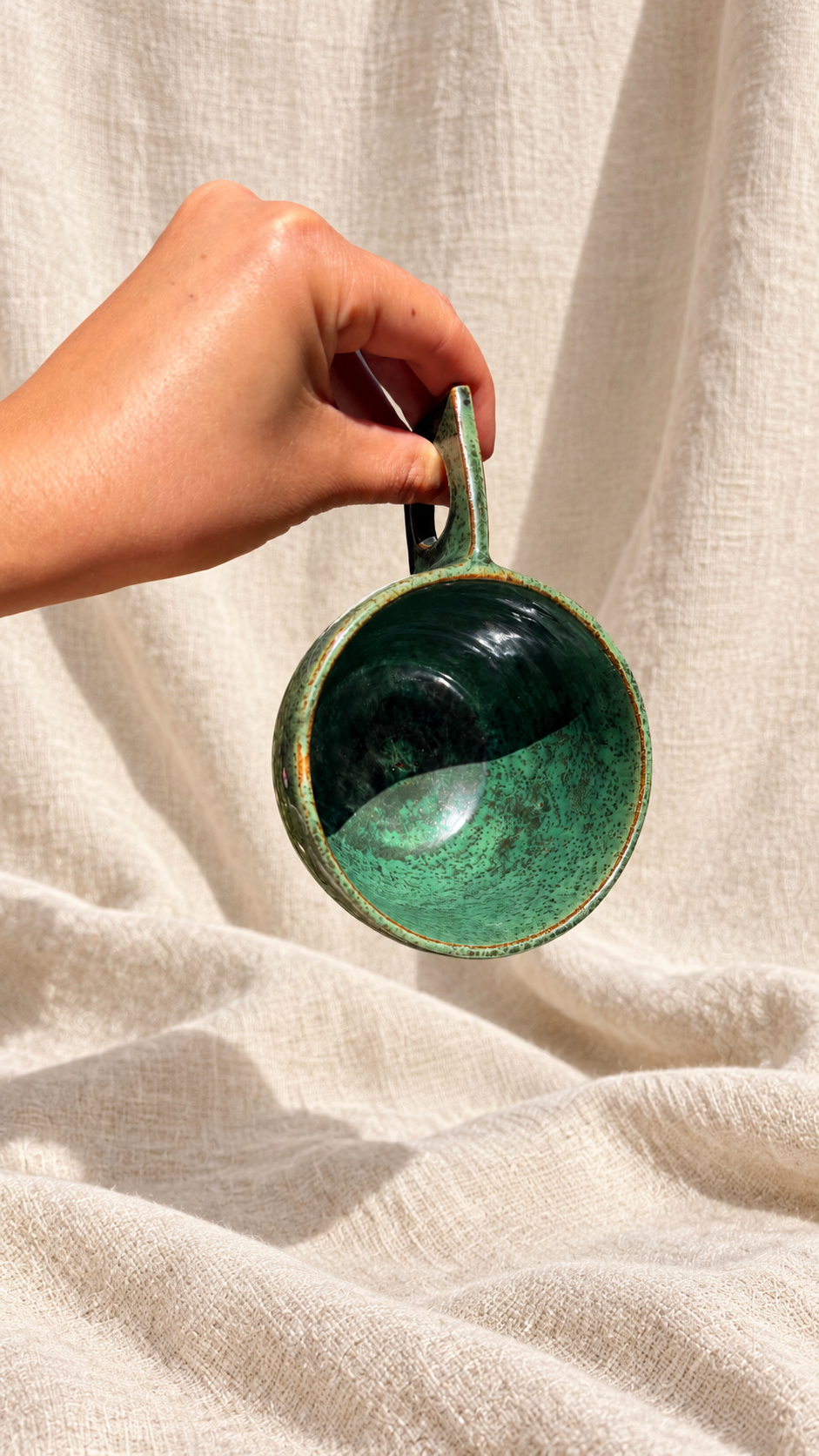 Forest green handmade ceramic mug with mottled glaze and a rectangular handle with a circular opening