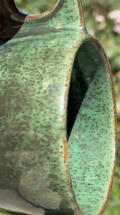 Forest green handmade ceramic mug with mottled glaze and a rectangular handle with a circular opening