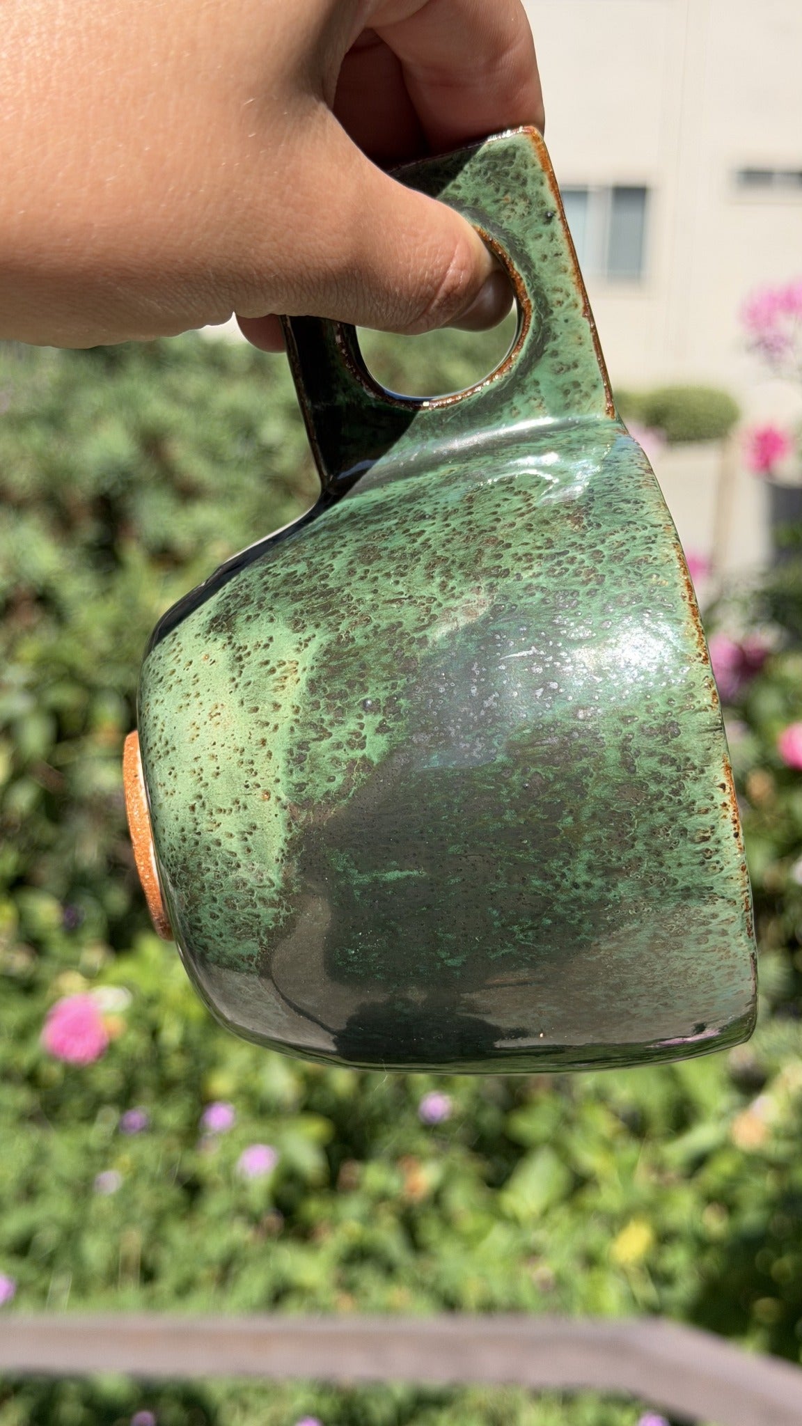 Forest green handmade ceramic mug with mottled glaze and a rectangular handle with a circular opening